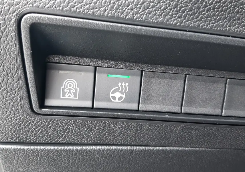 Gros plan sur les boutons de commande du Peugeot Rifter 2026, avec témoin vert sur le chauffage du volant.