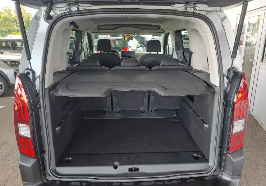 Vue arrière ouverte du coffre du Peugeot Rifter bleu Kiama, montrant l’espace de chargement et les sièges arrière rabattus.