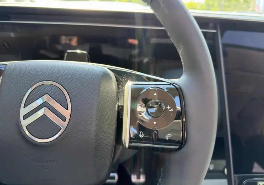 Gros plan sur le volant cuir du Citroën C5 Aircross gris platinium, avec commandes multifonctions et logo central chrome.
