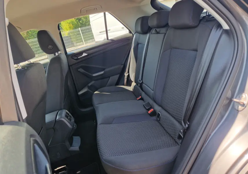 Vue intérieure côté droit des sièges arrière noirs du Volkswagen T-Roc gris foncé, montrant les appuie-têtes et ceintures.