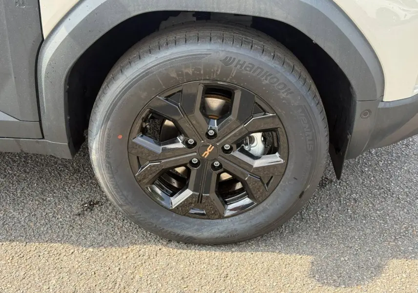 Gros plan sur la jante noire brillante et le pneu Hankook du Dacia Duster blanc côté avant droit.