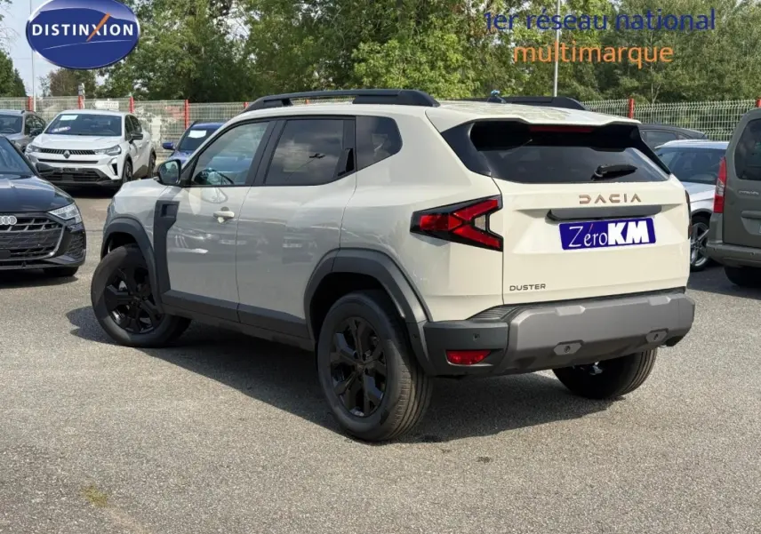 Vue 3/4 arrière droite d'un Dacia Duster blanc Glacier avec jantes noires et barres de toit noires.