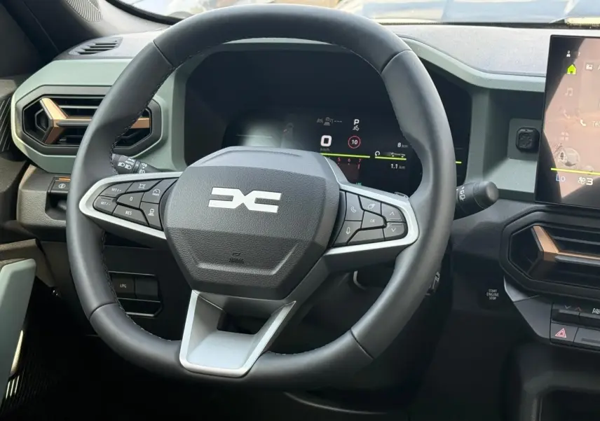 Vue rapprochée du volant noir multifonction du Dacia Duster 2026 avec tableau de bord numérique et écran tactile.