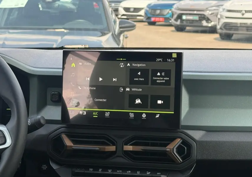 Vue intérieure du tableau de bord du Dacia Duster blanc 2026, avec écran tactile central et aérateurs hexagonaux.