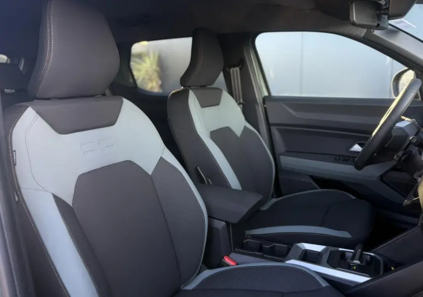 Vue intérieure côté conducteur du Dacia Duster 2026, sièges TEP MicroCloud gris clair et noir avec accoudoir central.