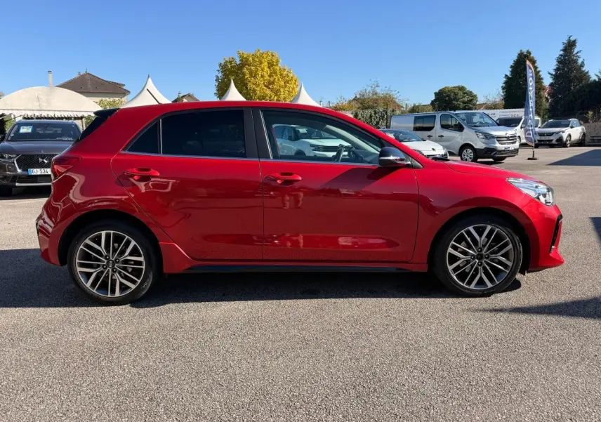 Profil côté gauche d'une KIA RIO rouge grenadine 2022, version GT-LINE, avec jantes alliage et vitres teintées.