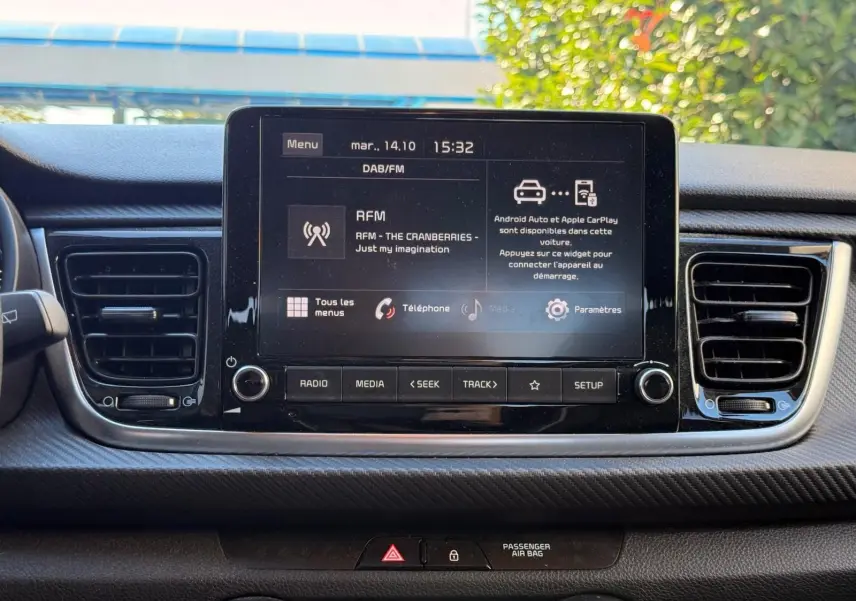 Écran tactile central de la Kia Rio 2022 affichant les options multimédia, entouré des aérateurs et commandes du tableau de bord.