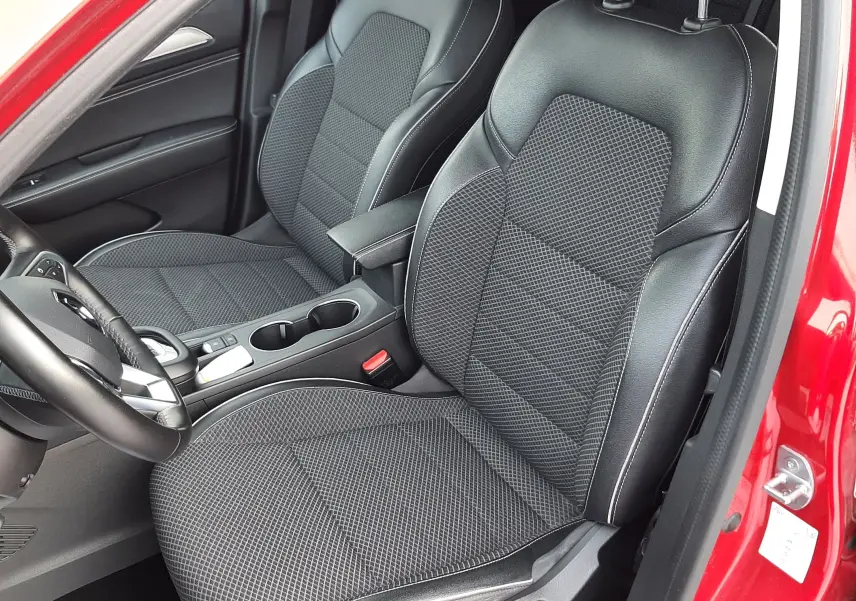 Vue intérieure côté gauche du Renault Arkana rouge Flame 2021, sièges avant noirs en tissu et cuir avec surpiqûres blanches.