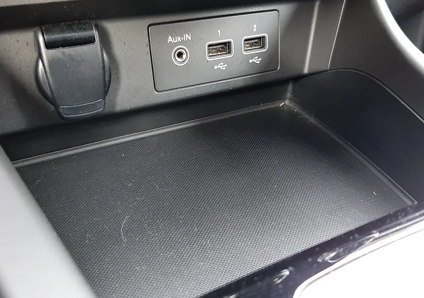 Gros plan sur la console centrale noire du Renault Arkana 1.6 E-TECH 145 Intens avec prises USB et Aux-In visibles.