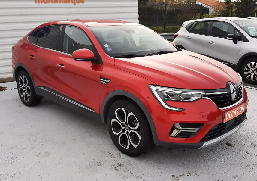 Renault Arkana rouge Flame en 3/4 avant droit, SUV hybride avec jantes noires et détails chromés visibles.