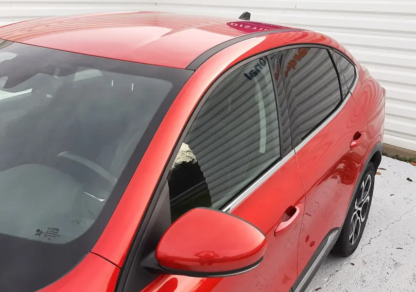 Vue 3/4 avant droit du Renault Arkana 1.6 E-TECH 145 Intens rouge flamme avec jantes alliage et vitres teintées.
