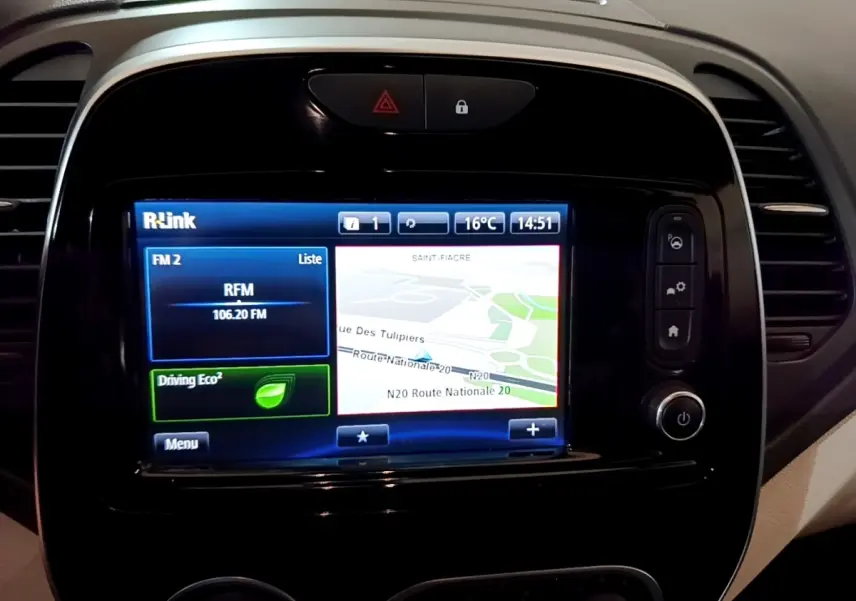 Gros plan sur l'écran tactile central du tableau de bord du Renault Captur Intens orange, affichant la navigation et la radio FM.