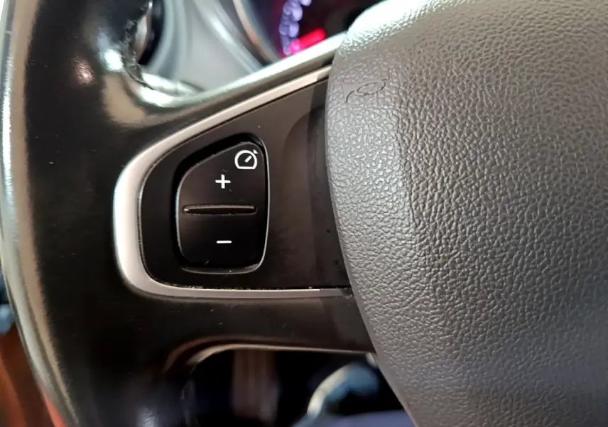 Gros plan sur les commandes de régulateur de vitesse au volant cuir du Renault Captur Intens orange 2019.