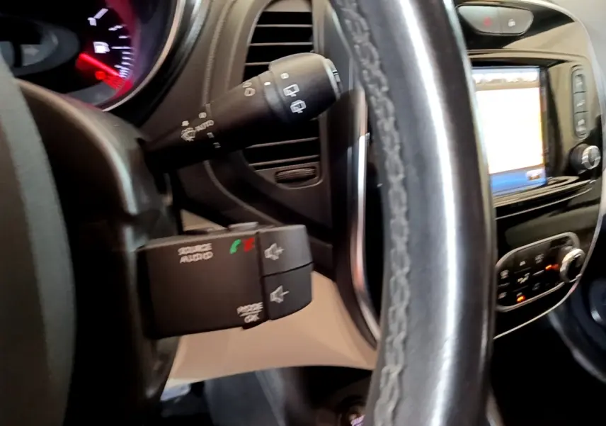 Vue rapprochée du volant cuir et du tableau de bord noir du Renault Captur Intens 2019 avec commandes audio au volant.