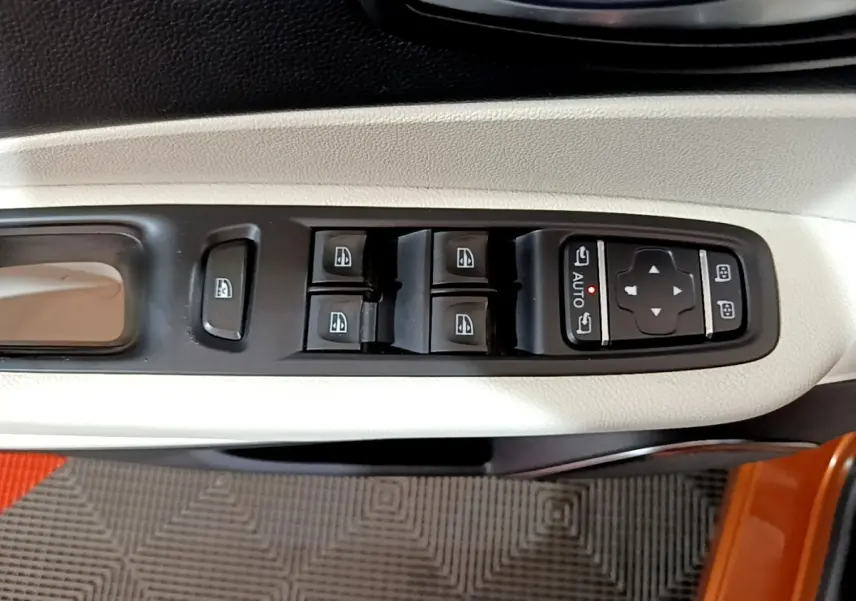 Vue rapprochée des commandes de lève-vitres et réglages des rétroviseurs sur la porte côté gauche du Renault Captur orange.