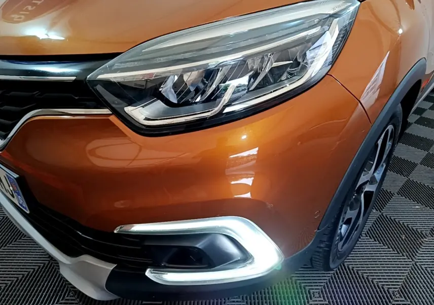 Gros plan sur l'avant droit orange du Renault Captur 2019, mettant en valeur son phare LED et la signature lumineuse chromée.