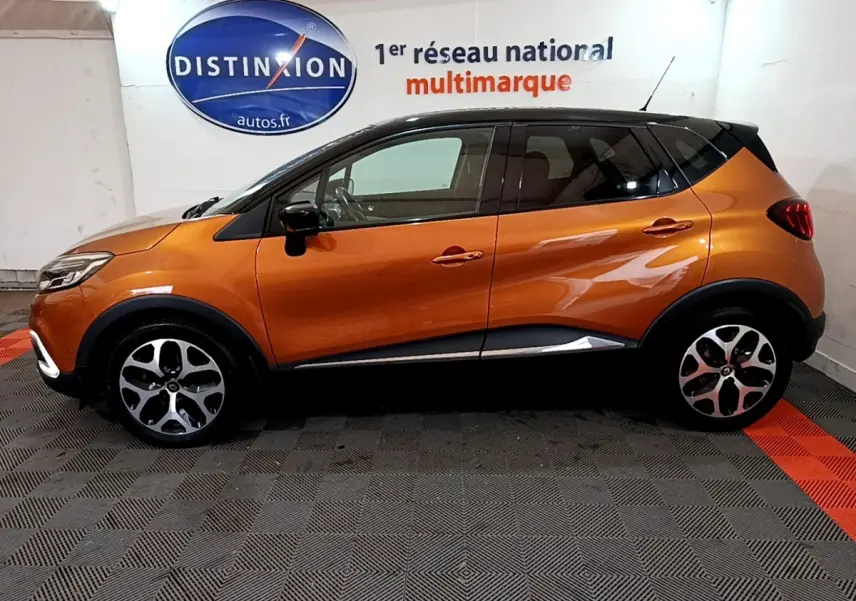 Profil côté gauche d'un Renault Captur Intens orange 2019 avec toit noir dans un showroom Distinxion.