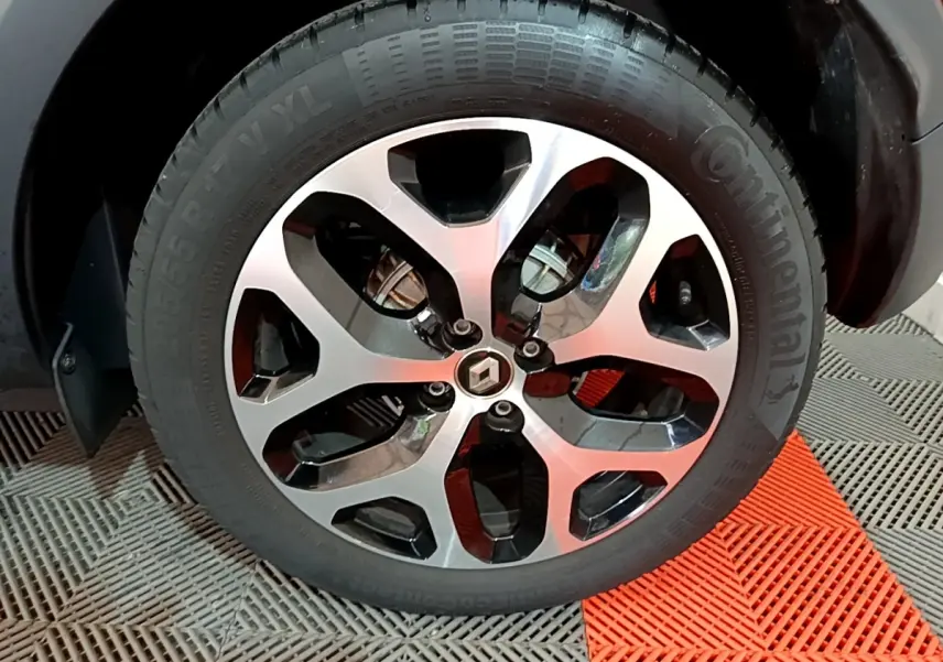 Gros plan sur la jante alliage noire et argentée du Renault Captur orange, avec logo Renault au centre.