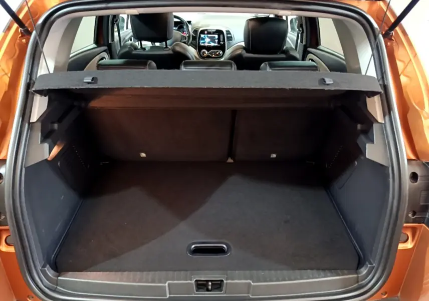 Coffre ouvert vu de l'arrière d'un Renault Captur orange 2019 avec tablette cache-bagages et sièges arrière noirs visibles.