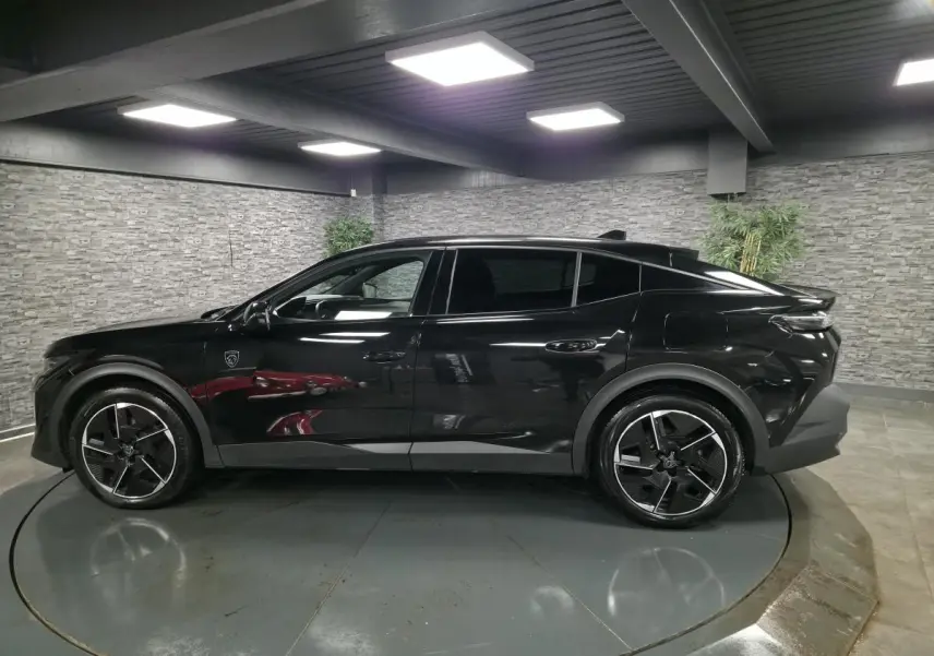 Peugeot 408 noire vue de profil droit en intérieur, avec jantes alliage 19 pouces et toit noir Mistral.