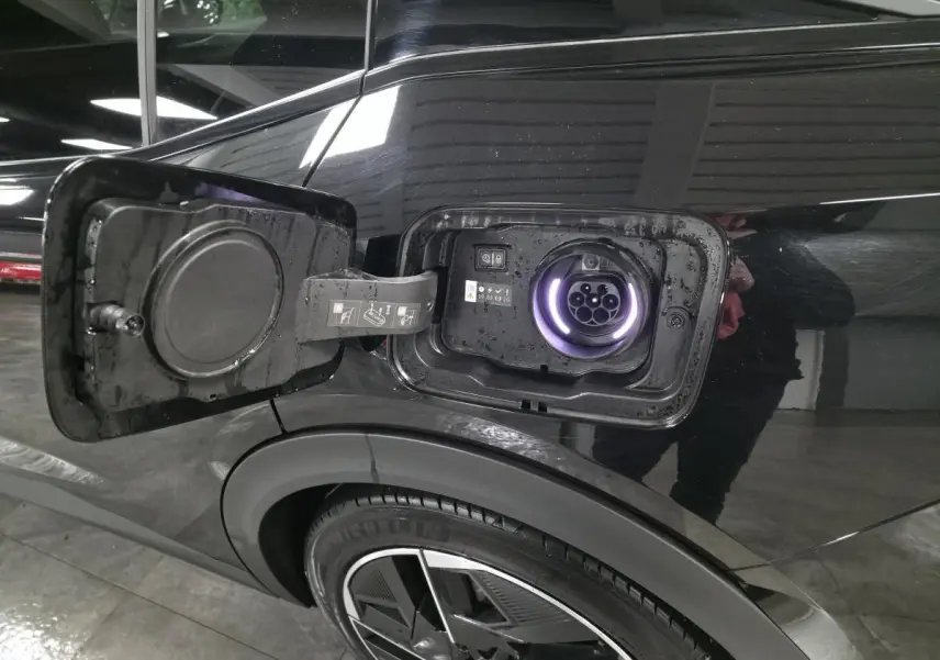 Prise de recharge ouverte côté gauche arrière d’une Peugeot 408 noire, avec jante alliage 19 pouces visible.