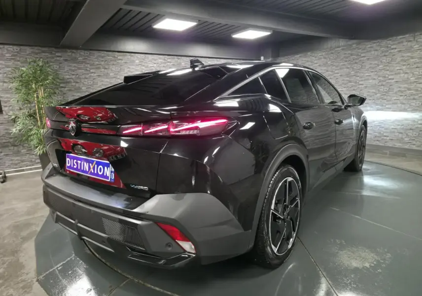 Vue 3/4 arrière droite d'une Peugeot 408 noire avec feux arrière LED distinctifs dans un showroom.