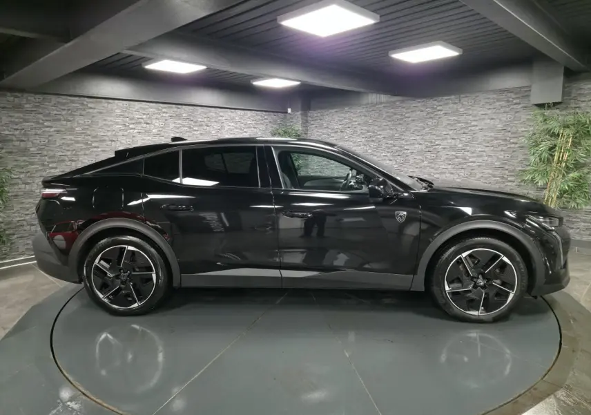 Vue latérale droite d'une Peugeot 408 noire brillante avec jantes alliage 19 pouces et badge lion sur l'aile avant.