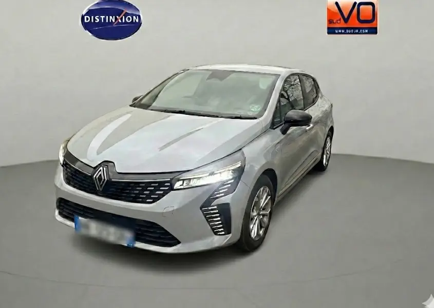 Renault Clio gris en vue 3/4 avant droit, avec calandre noire et feux LED distinctifs allumés.