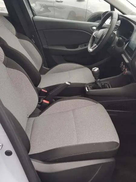 Vue intérieure côté conducteur de la Renault Clio gris 2025 avec boîte manuelle et sièges tissu clair.