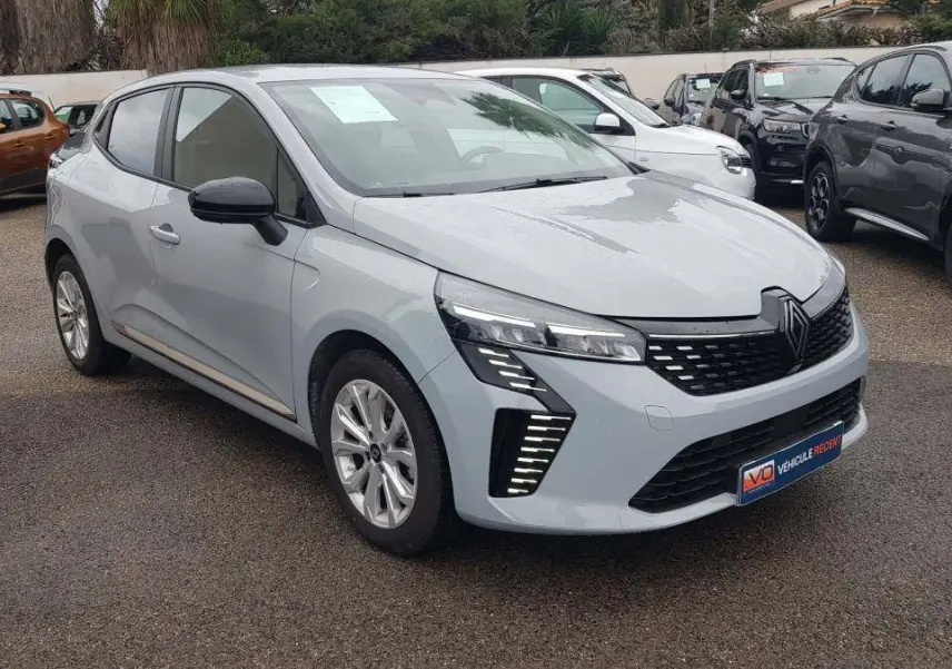 Renault Clio gris vue 3/4 avant droit, avec feux LED distinctifs et vitres surteintées en extérieur.