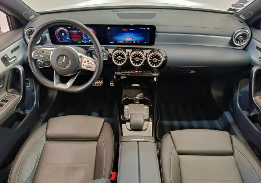 Vue intérieure avant de la Mercedes Classe A A 250 e AMG Line 2021, tableau de bord noir avec écran tactile et volant cuir alu multifonctions.