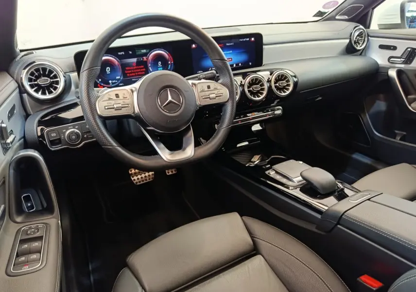 Intérieur de la Mercedes Classe A 250 e AMG Line 2021, vue avant centrée sur le volant cuir alu et tableau de bord numérique.