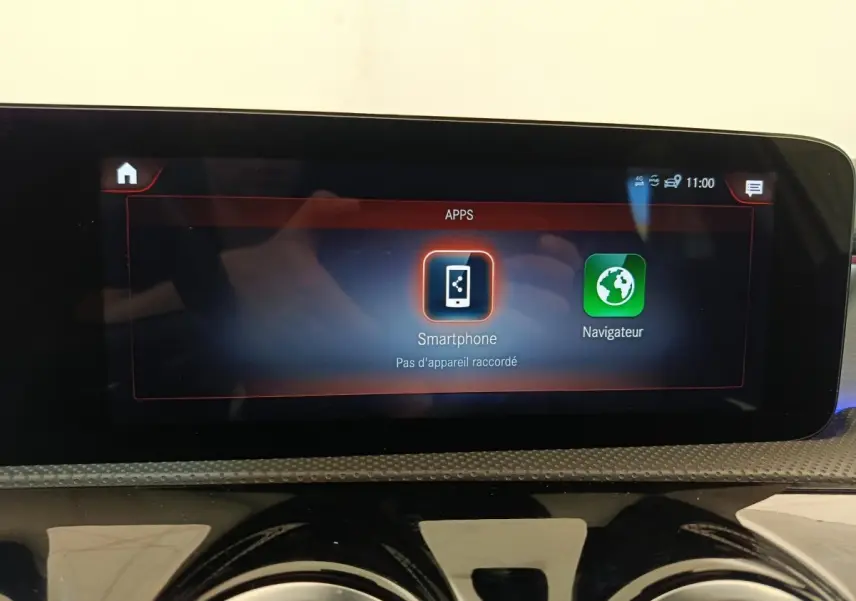 Écran tactile central affichant les applications smartphone et navigateur dans une Mercedes Classe A blanche.