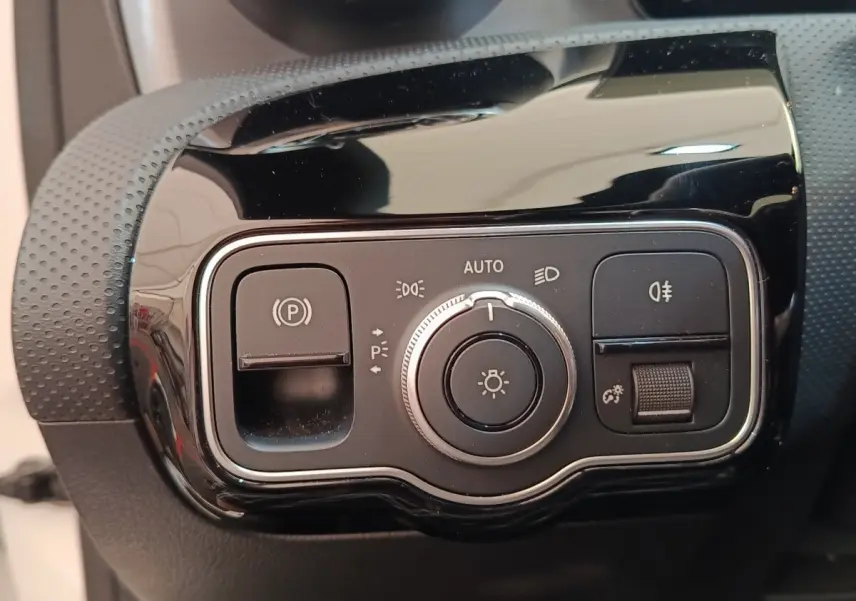 Gros plan sur le panneau de commande des phares et du frein à main électrique de la Mercedes Classe A blanche.