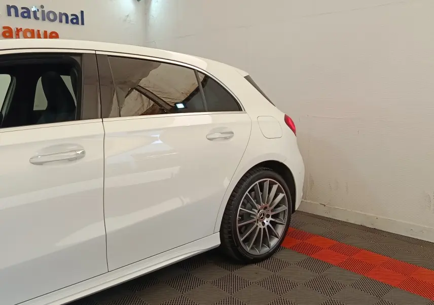 Vue latérale arrière droite d'une Mercedes Classe A blanche avec jantes AMG et rétroviseurs rabattables électriquement.