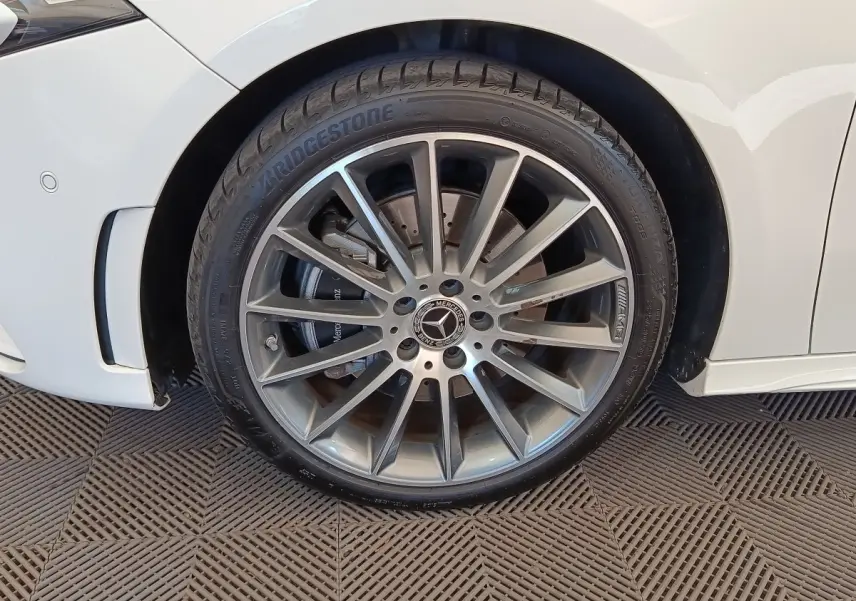 Gros plan sur la roue avant droite argentée AMG d'une Mercedes Classe A blanche, avec pneu Bridgestone visible.