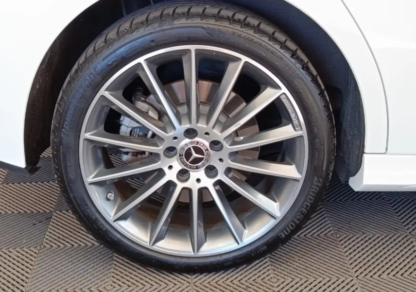 Gros plan sur la roue avant droite argentée AMG d'une Mercedes Classe A blanche, avec pneu Bridgestone visible.