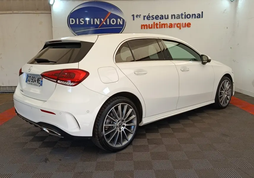 Vue 3/4 arrière droite d'une Mercedes Classe A blanche A 250 e AMG Line avec jantes alliage et vitres teintées.
