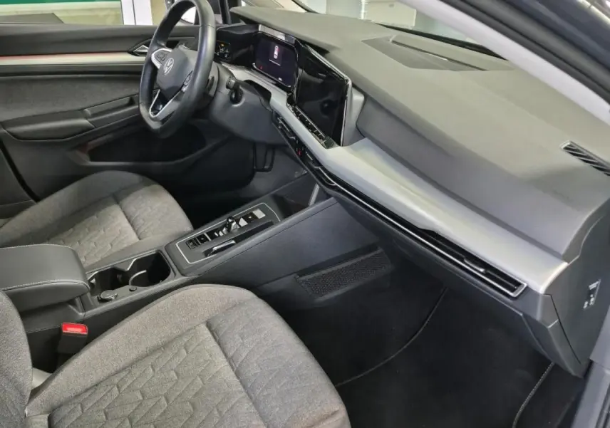 Intérieur avant droit de la Volkswagen Golf 8 gris Urano, avec tableau de bord numérique et sièges tissu gris.