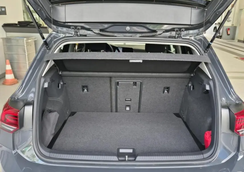 Coffre ouvert vu de l'arrière d'une Volkswagen Golf 8 gris Urano, montrant l'espace de chargement et la plage arrière.