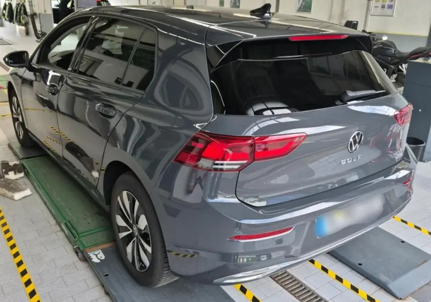 Vue 3/4 arrière droite d'une Volkswagen Golf 8 gris Urano avec feux arrière LED et jantes alliage Norfolk.
