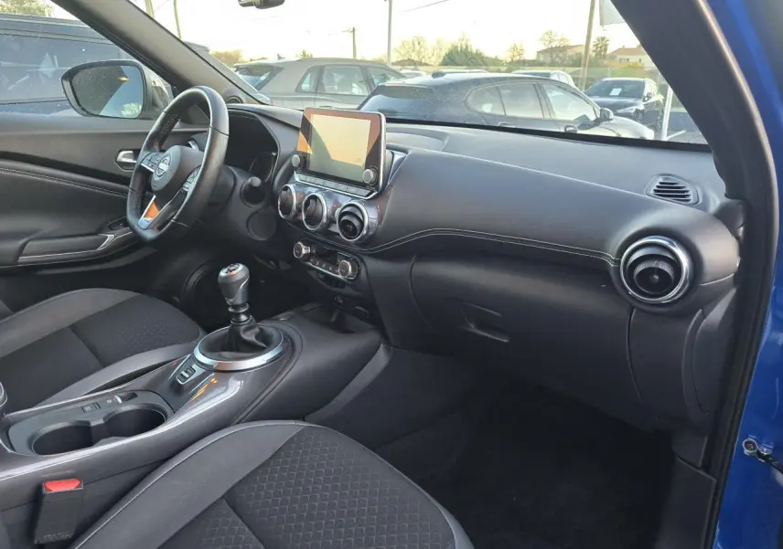 Intérieur côté passager du Nissan Juke II bleu magnetic 2024, avec tableau de bord noir et console centrale moderne.