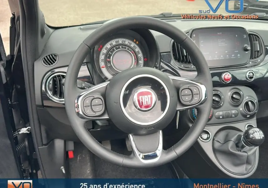 Vue intérieure centrée sur le volant et le tableau de bord noir de la FIAT 500C 2024 avec boîte manuelle et écran tactile.
