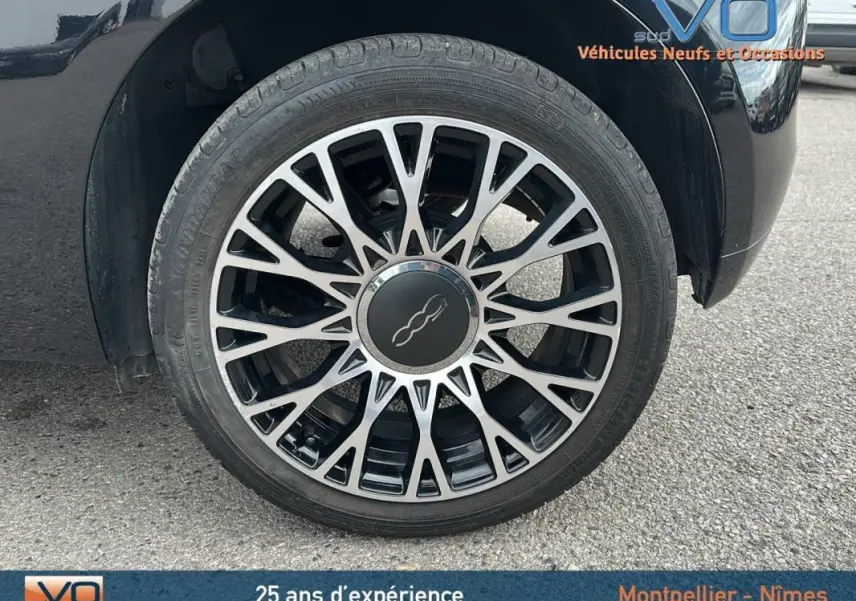 Gros plan sur la roue avant gauche noire de la FIAT 500C 2024 avec jante en alliage au design étoilé.