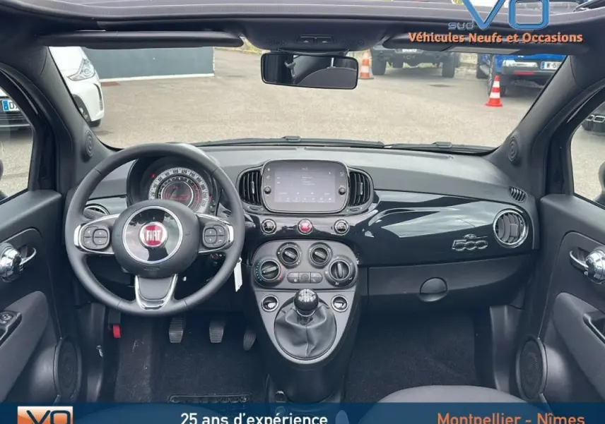 Tableau de bord noir de la Fiat 500C 2024 hybride, vue frontale avec volant et écran tactile central.