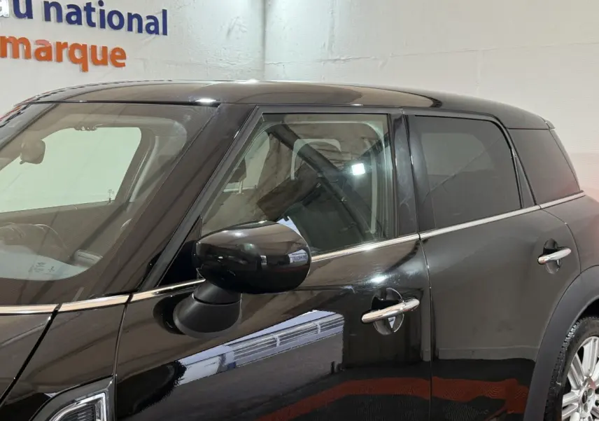 Vue côté gauche rapprochée d'une MINI COUNTRYMAN noire 2020 avec rétroviseur et poignées chromés visibles.