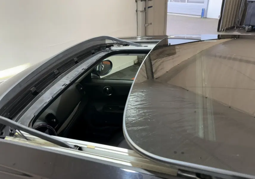 Vue plongeante sur le toit ouvrant panoramique ouvert d'une MINI Countryman noire, montrant l'intérieur côté conducteur.