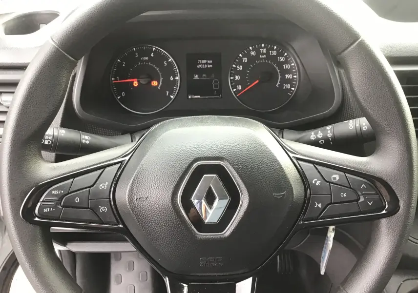 Vue rapprochée du volant noir de Renault Trafic Combi gris Highland, avec commandes intégrées et tableau de bord visible.