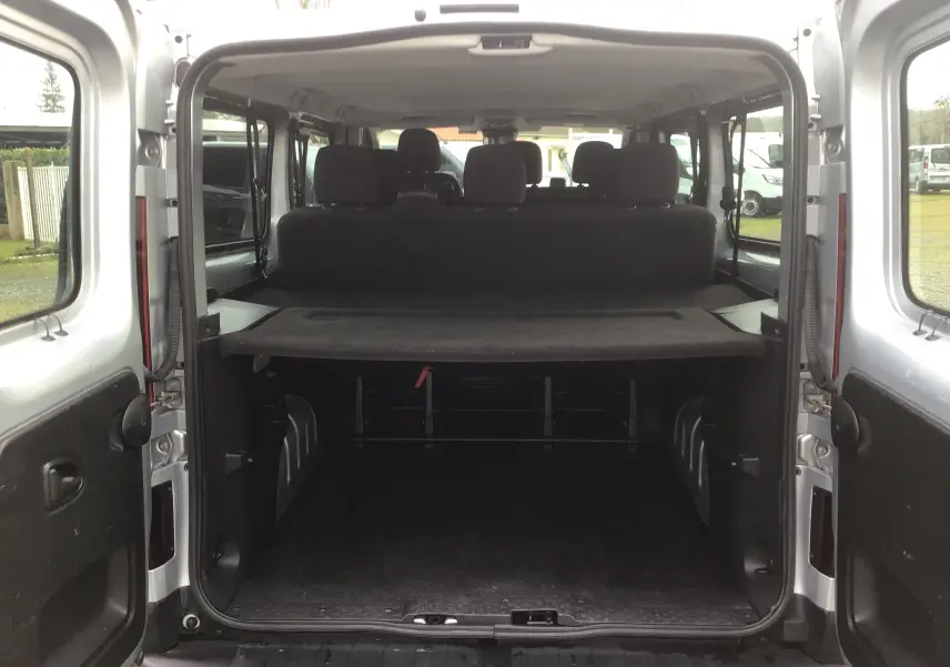 Vue arrière ouverte du Renault Trafic Combi gris Highland montrant l'espace de chargement et les sièges arrière.