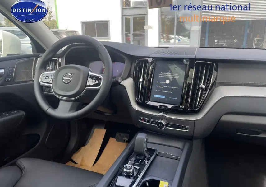 Vue intérieure avant du tableau de bord et volant noir du Volvo XC60 T6 hybride rechargeable 2024 avec écran tactile vertical.